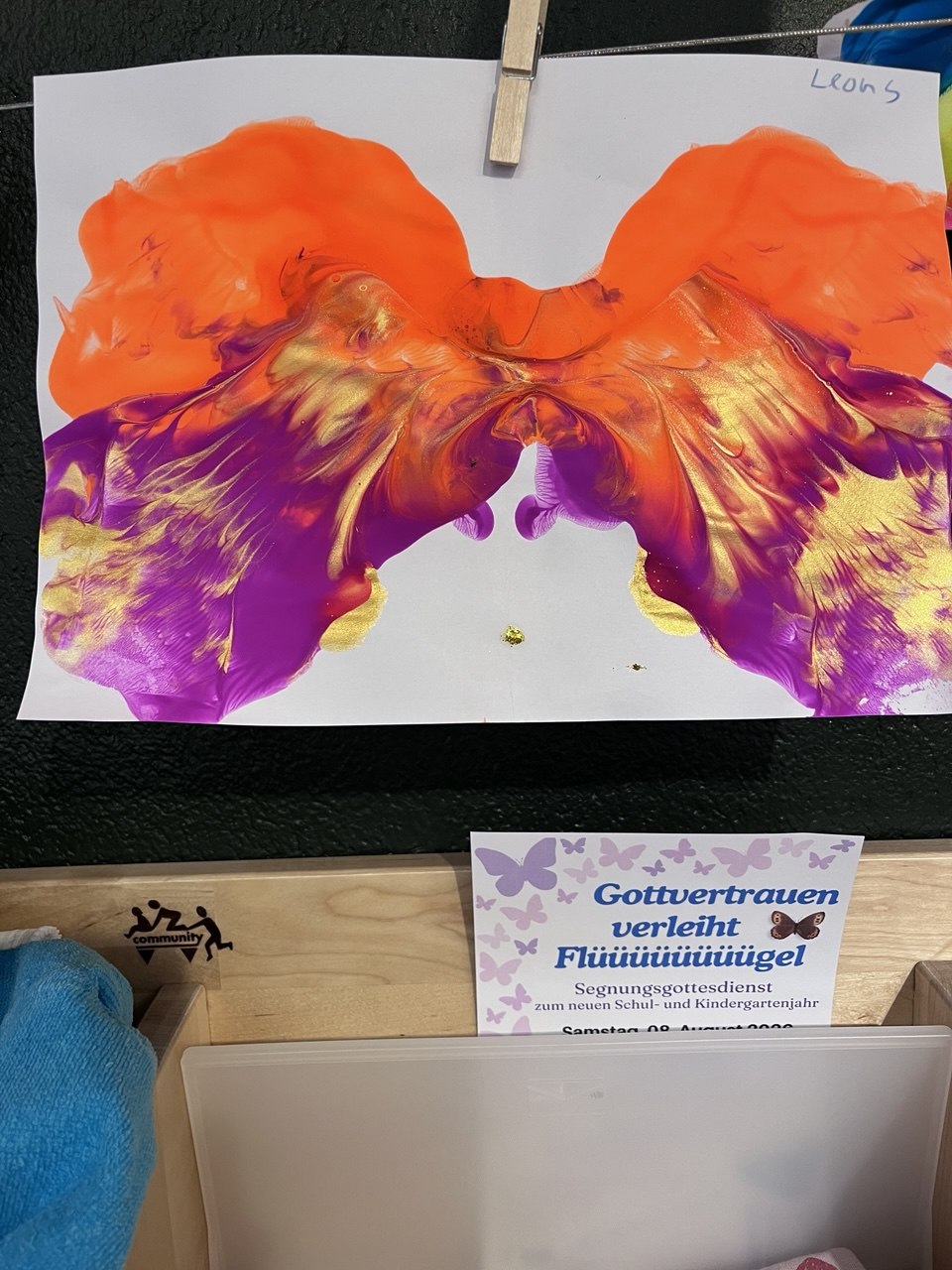 Orange, purple, and gold wing-shaped painting created by Nina’s son