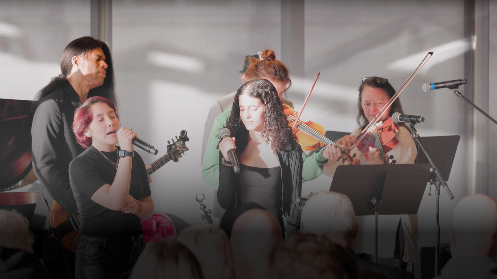Young musicians singing and playing instruments together at a MusicOne performance
